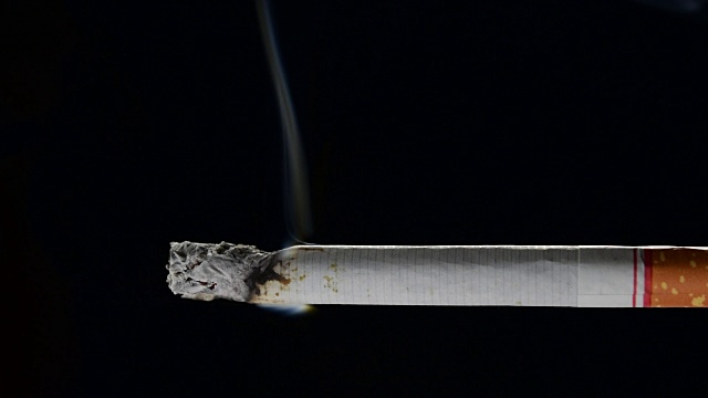 黑色背景上点燃和燃烧的香烟的镜头视频素材