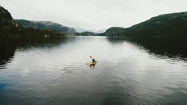 鸟瞰图的女人皮划艇上的湖在山上视频下载