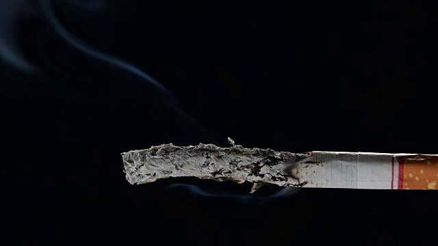 黑色背景上点燃和燃烧的香烟的镜头视频素材