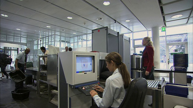 德国慕尼黑，商务人士通过机场安检时安检人员正在检查x光监视器视频下载