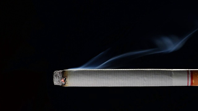 慢镜头点燃和燃烧的香烟与烟雾在黑色的背景视频下载