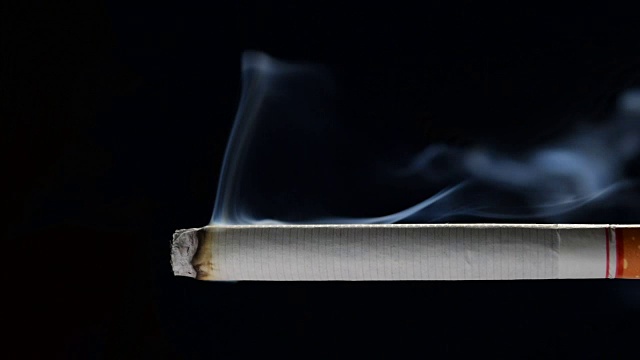正常速度的镜头点燃和燃烧的香烟与烟雾在黑色的背景视频素材