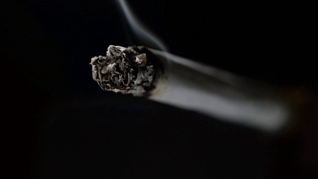 慢镜头点燃和燃烧的香烟与烟雾在黑色的背景视频素材