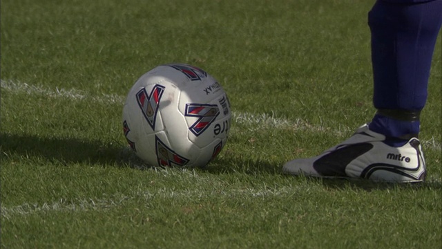 CU足球运动员将球放在场地上，然后踢球并追着球跑/谢菲尔德，英格兰，英国视频素材