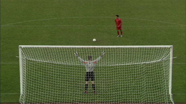 在点球大战中，当守门员扑向球时，足球运动员将球踢进球门/谢菲尔德，英格兰，英国视频素材