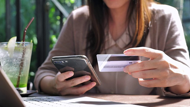 近距离观察年轻的亚洲女性用信用卡在手机上购物视频下载