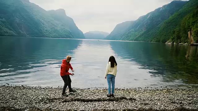 女人和男人在挪威的峡湾里扔石头视频素材