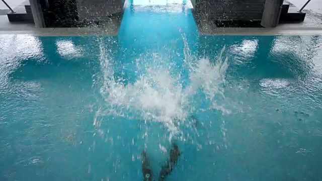 在酒店的室内游泳池区域白天SPA -晒黑的有吸引力的运动男子在他的30多岁，黑色短发，绿松石游泳短裤，跳进蓝色的热水，上来和游泳出框上锁的相机视频下载