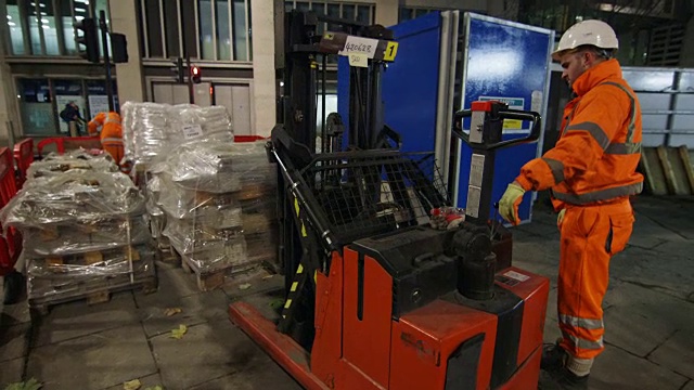 英国伦敦，建筑工人晚上在托盘千斤顶上装载托盘视频素材