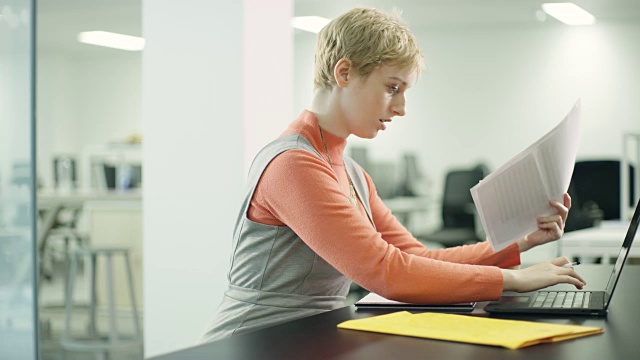 微软女商人在办公桌前处理文件和笔记本电脑视频素材