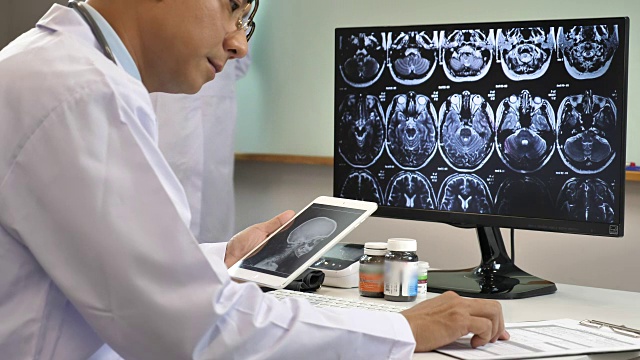 医生在电脑和平板电脑上检查核磁共振扫描，慢动作视频下载