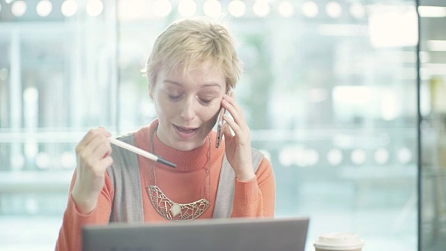 商务女性在办公桌上用手提电脑打电话视频素材