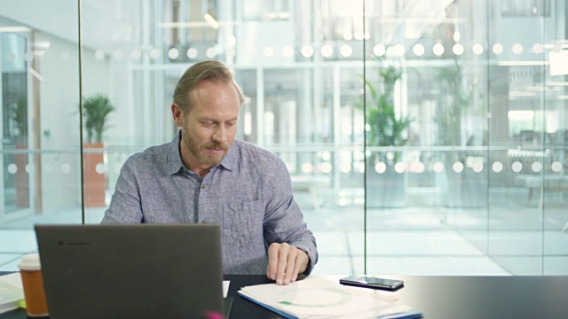 在董事会会议室里，微软商人在办公桌前工作，带着文件和笔记本电脑视频素材