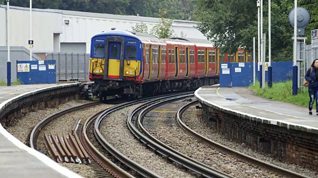 英国伦敦，一名女子沿着诺宾顿火车站站台走着，火车离开视频素材