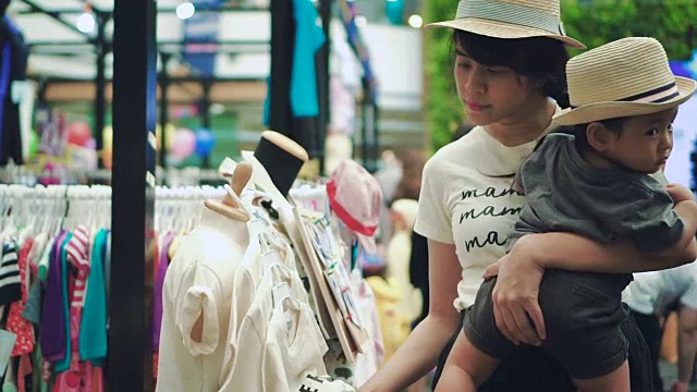 亚洲母亲和小男孩在跳蚤市场购物视频素材