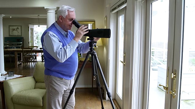 一个老人用望远镜从露台门往外看视频素材