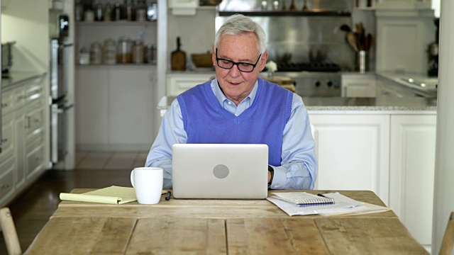 一个老男人在餐厅里用笔记本电脑工作视频下载