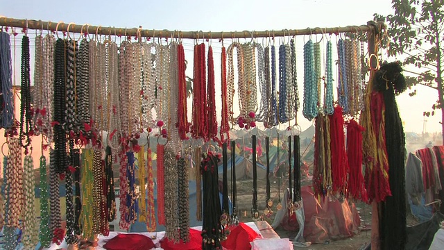 MA, TD，印度北方邦阿拉哈巴德的市场摊位，架子上挂着彩色的珠子和成堆的红色赭色颜料视频素材