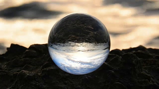 玻璃球在海浪前的岩石上视频下载