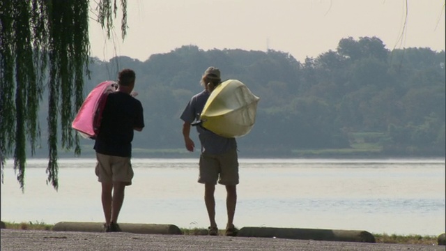 两名男子背着皮划艇，在美国德克萨斯州的湖边放下视频素材