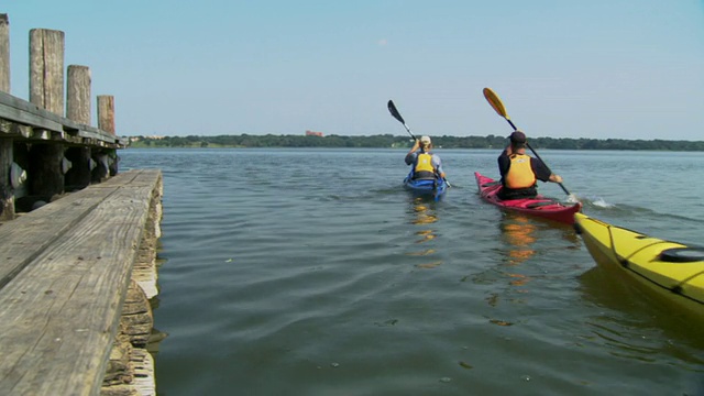 三名男子划着皮划艇经过湖上的码头/白石湖，达拉斯，德克萨斯州，美国视频素材