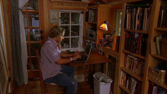 美国加州坎布里亚，一个年轻人在家里使用笔记本电脑视频素材