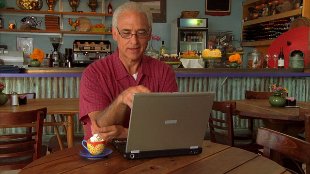 美国加州，摩洛湾，一名在咖啡店使用笔记本电脑的成年人视频素材