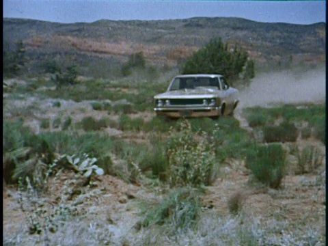 蒙太奇WS AMC Rebel驾驶穿过沙漠，向相机/ MS Rebel驾驶越过山丘，远离相机/美国视频素材