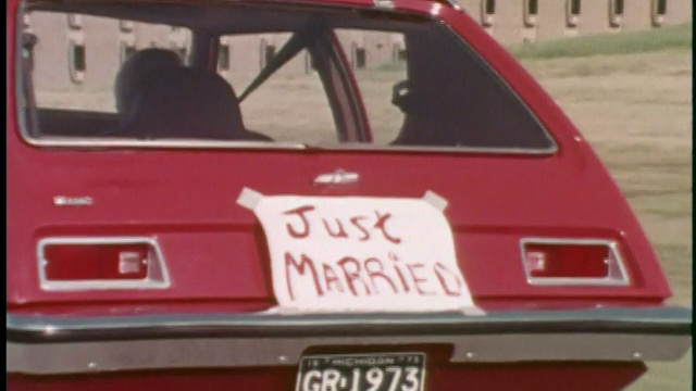 CU ZO 1973红色AMC Gremlin开车在路上，后面有“刚刚结婚”的标志/ USA视频下载