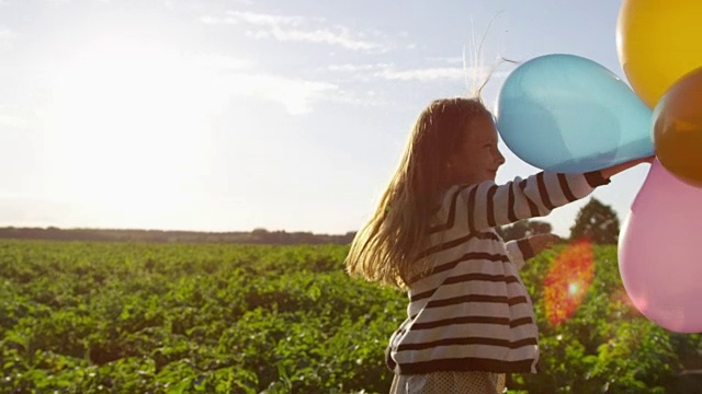 气球在小女孩的手在户外玩跳舞的慢动作视频素材
