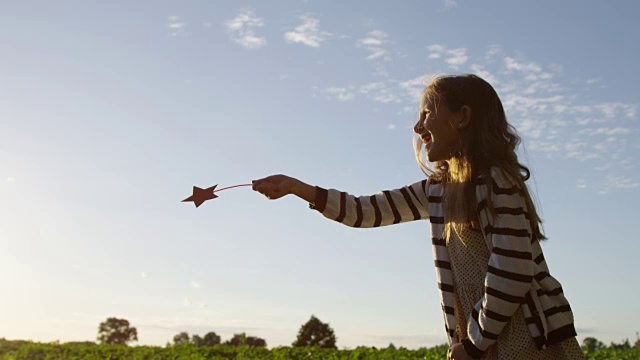 手握魔术棒，小女孩在日落时分假装和模仿视频素材