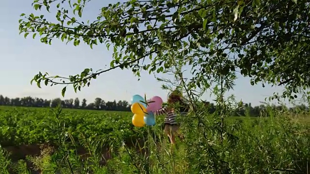 和气球一起奔跑绿色田野里的小女孩背光视频素材