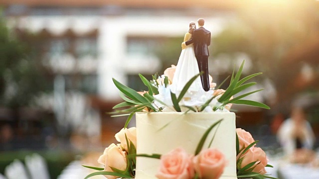 优雅的婚礼蛋糕与新娘和新郎雕像装饰鲜花。视频下载