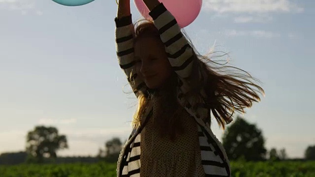微笑的小女孩手里拿着气球在户外视频素材