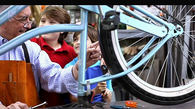 孙子在车间和爷爷一起修自行车。视频下载