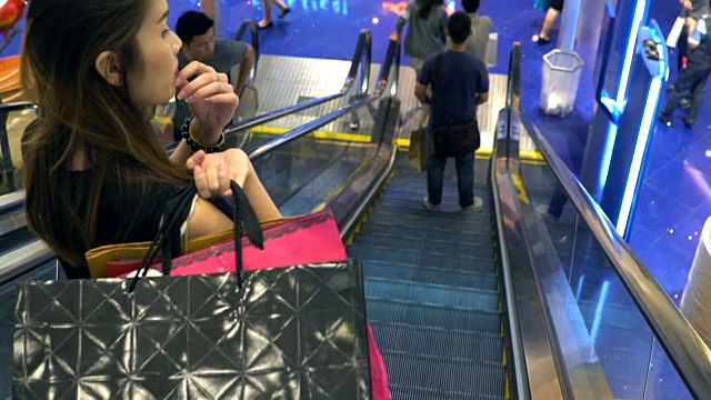 在自动扶梯上用购物袋购物的顾客视频素材