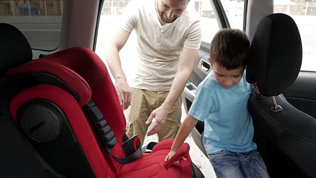 微笑的儿子在婴儿汽车座椅被放在后座的关怀父亲视频素材