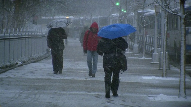 广角镜头下的行人在伞下走在人行道上的雪天/纽约市视频下载