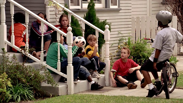 中镜头平移放大缩小孩子坐在门廊上传递足球来回视频下载