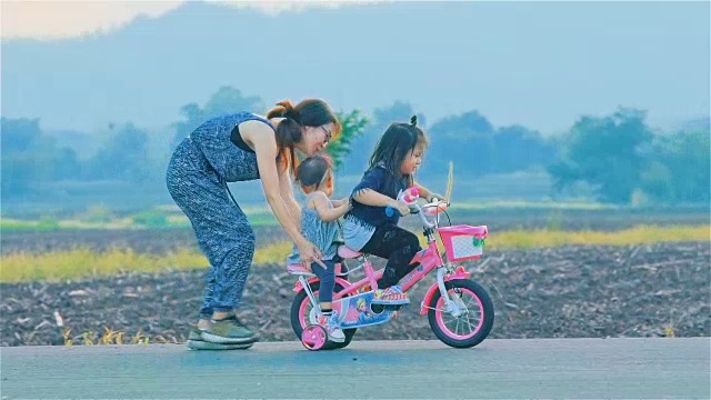 妈妈和她的女儿一起骑着自行车在乡下视频素材