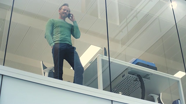 在现代化的办公室里，商人通过窗口打电话和查阅文件的情景视频素材
