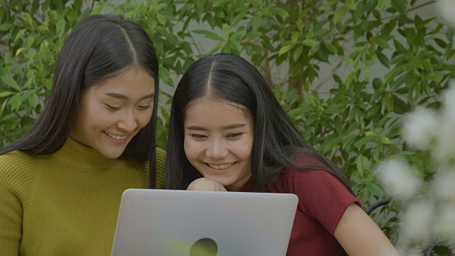 两个兴奋的亚洲漂亮女孩使用笔记本电脑，在网上购物视频素材