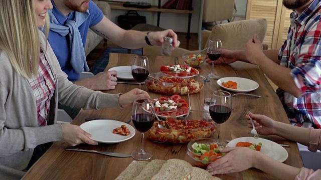 一群快乐的朋友享受午餐，在餐桌上吃健康的食物。视频素材
