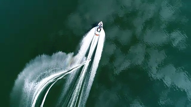 一个年轻人在湖上的小船后面滑水时做出完美的s型转弯视频下载