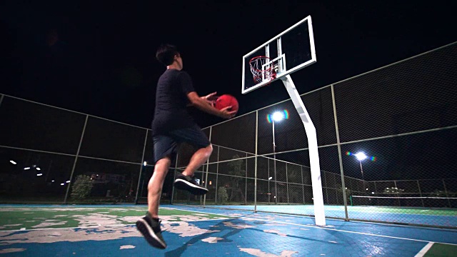 SLO MO运动概念:一个人在晚上独自在室外球场打篮球。视频下载