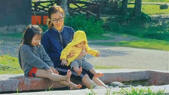 年轻的母亲和两个女儿在公园里玩视频素材