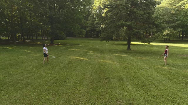 两个女人在草坪上打羽毛球。低空无人机视频视频素材