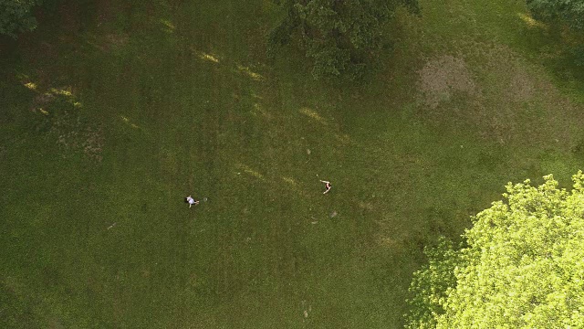 两个女人在草坪上打羽毛球。俯视图直接上方，无人机视频视频素材