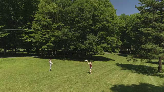 少女和年轻女子在草坪上打排球。低空无人机视频视频下载