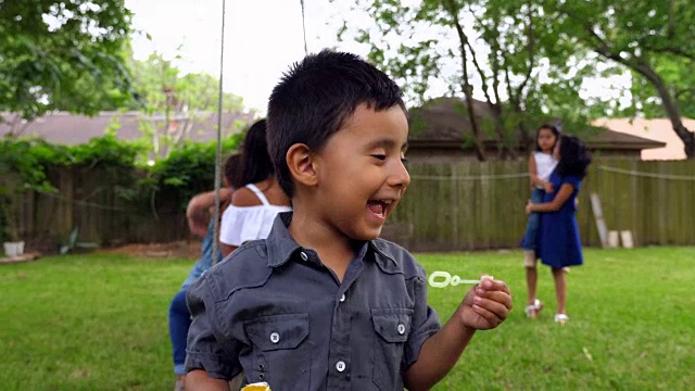 笑着的小男孩在后院派对上玩泡泡视频素材